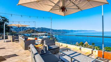 Une terrasse sur le toit, dotée d’un espace extérieur aménagé, d’un grand parasol et offrant une vue sur l’océan.