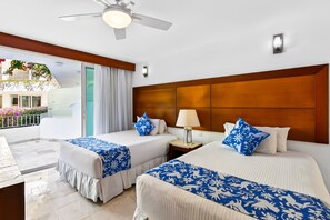 Une chambre d’hôtel avec deux lits, un balcon, un ventilateur de plafond et une vue sur un balcon orné de fleurs.