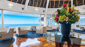 A spacious lobby with a large glass table, comfortable seating, and a view of the ocean. - Stylish Hillside Suite W/rooftop Pool, gym Access, AC & Family-friendly Layout (Puerto Vallarta)