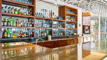Un bar doté de plusieurs étagères remplies de bouteilles d’alcool, d’un comptoir en granit poli et d’un design de plafond moderne.