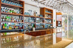 A bar with multiple shelves of liquor bottles, a polished granite countertop, and a modern ceiling design. - Stylish Hillside Suite W/rooftop Pool, gym Access, AC & Family-friendly Layout (Puerto Vallarta)