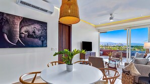 A modern living room with a dining area, large windows, and a ceiling fan. - D'toscana Residencial, PH #2 Apartment in Nuevo Vallarta (Nuevo Nayarit)