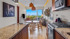 A modern kitchen with a central island, a large window, and a view of the cityscape. - D'toscana Residencial, PH #2 Apartment in Nuevo Vallarta (Nuevo Nayarit)