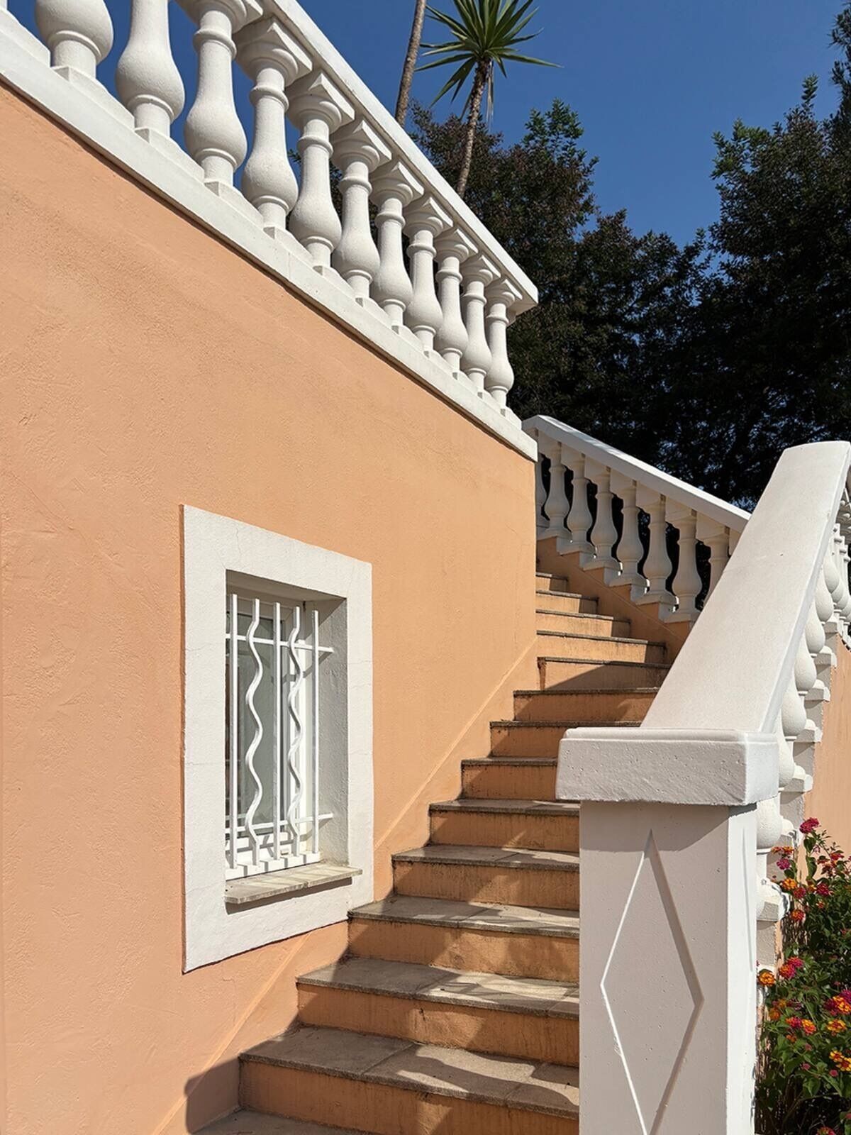 Un escalier avec des rampes blanches menant à un balcon doté d’une fenêtre.