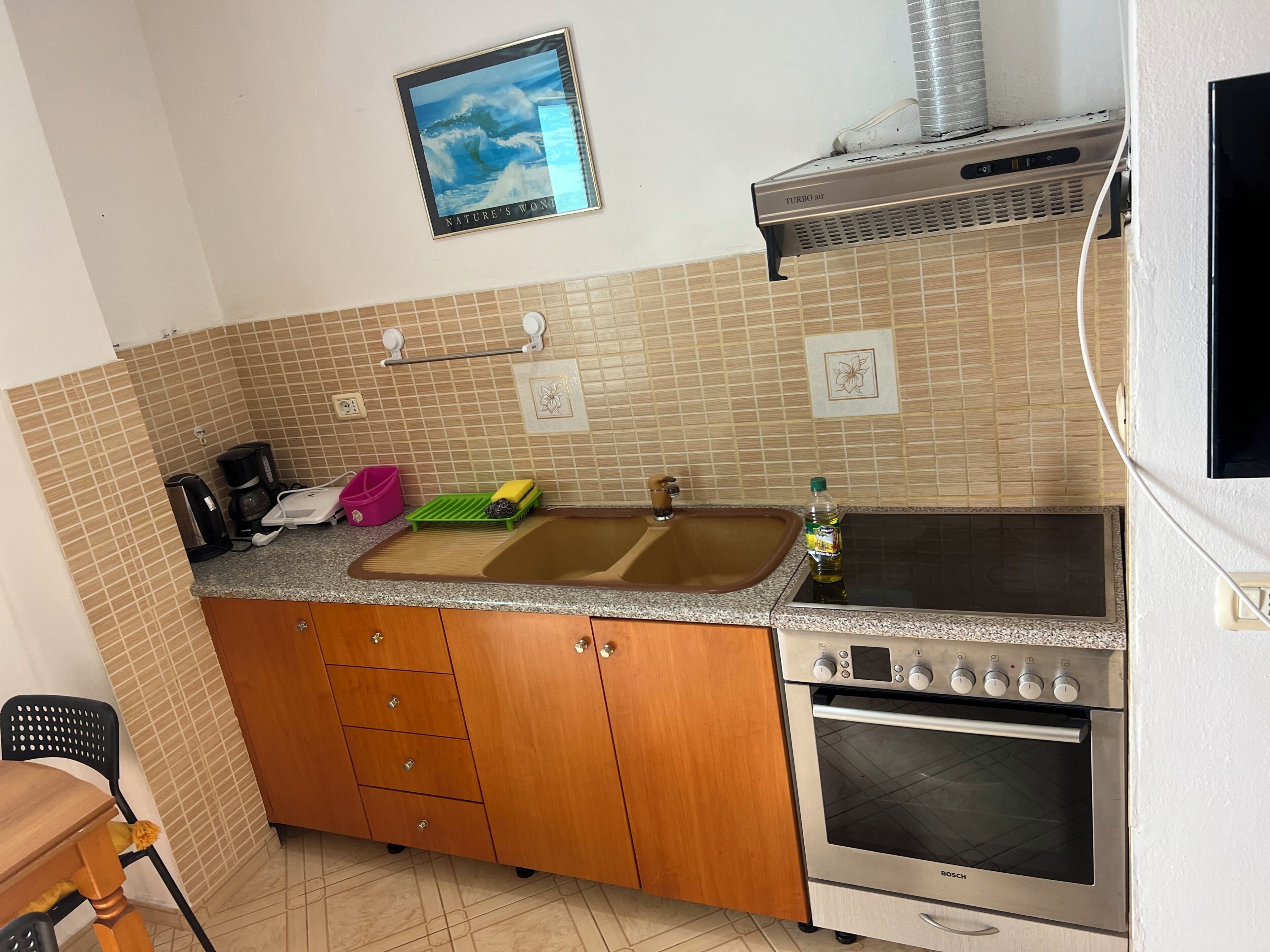 Cocina compacta con horno Bosch, un lavamanos, cafetera y una pequeña encimera.