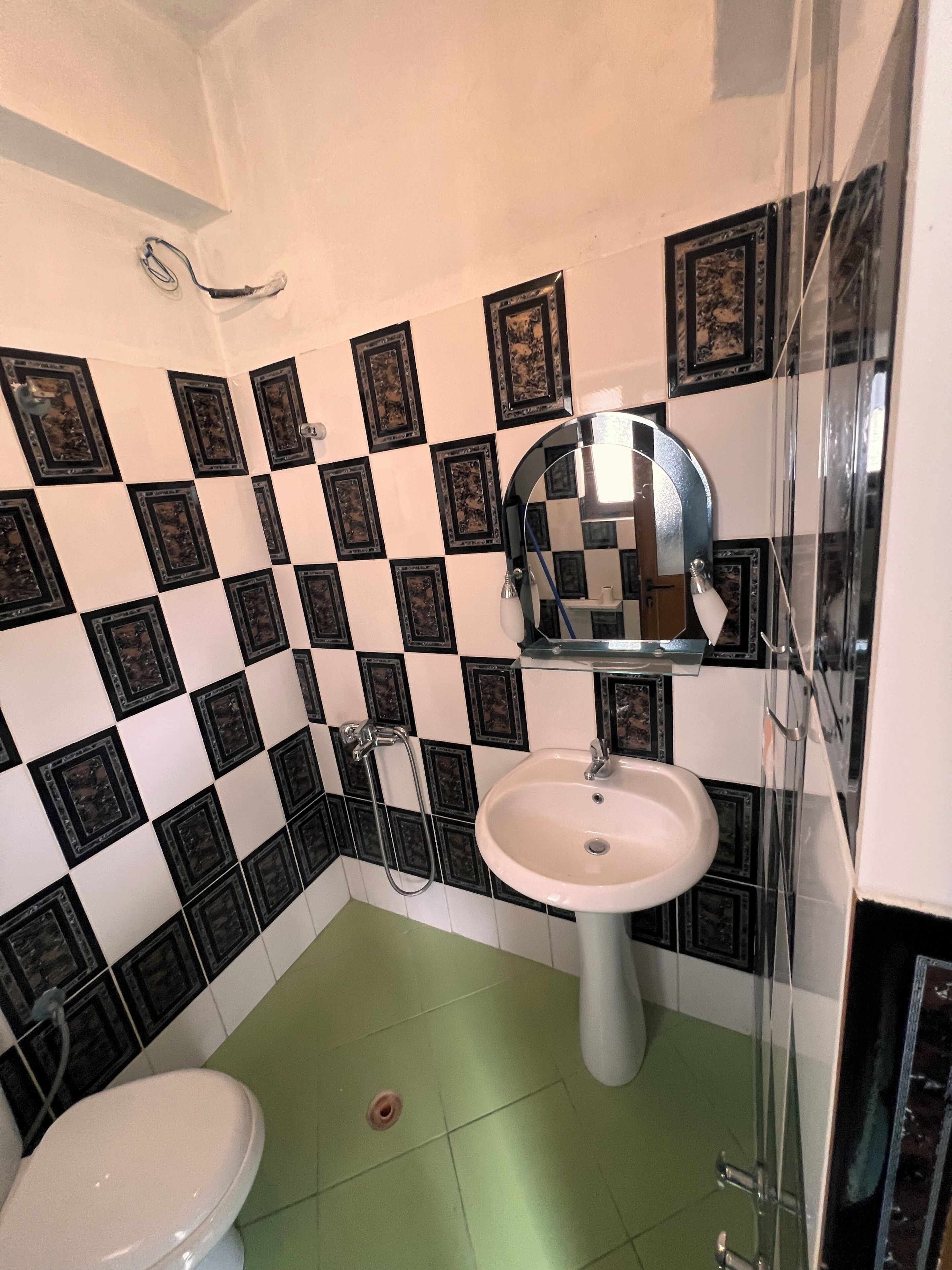 Une salle de bain avec un carrelage à motifs géométriques, un lavabo, des toilettes et une douche.