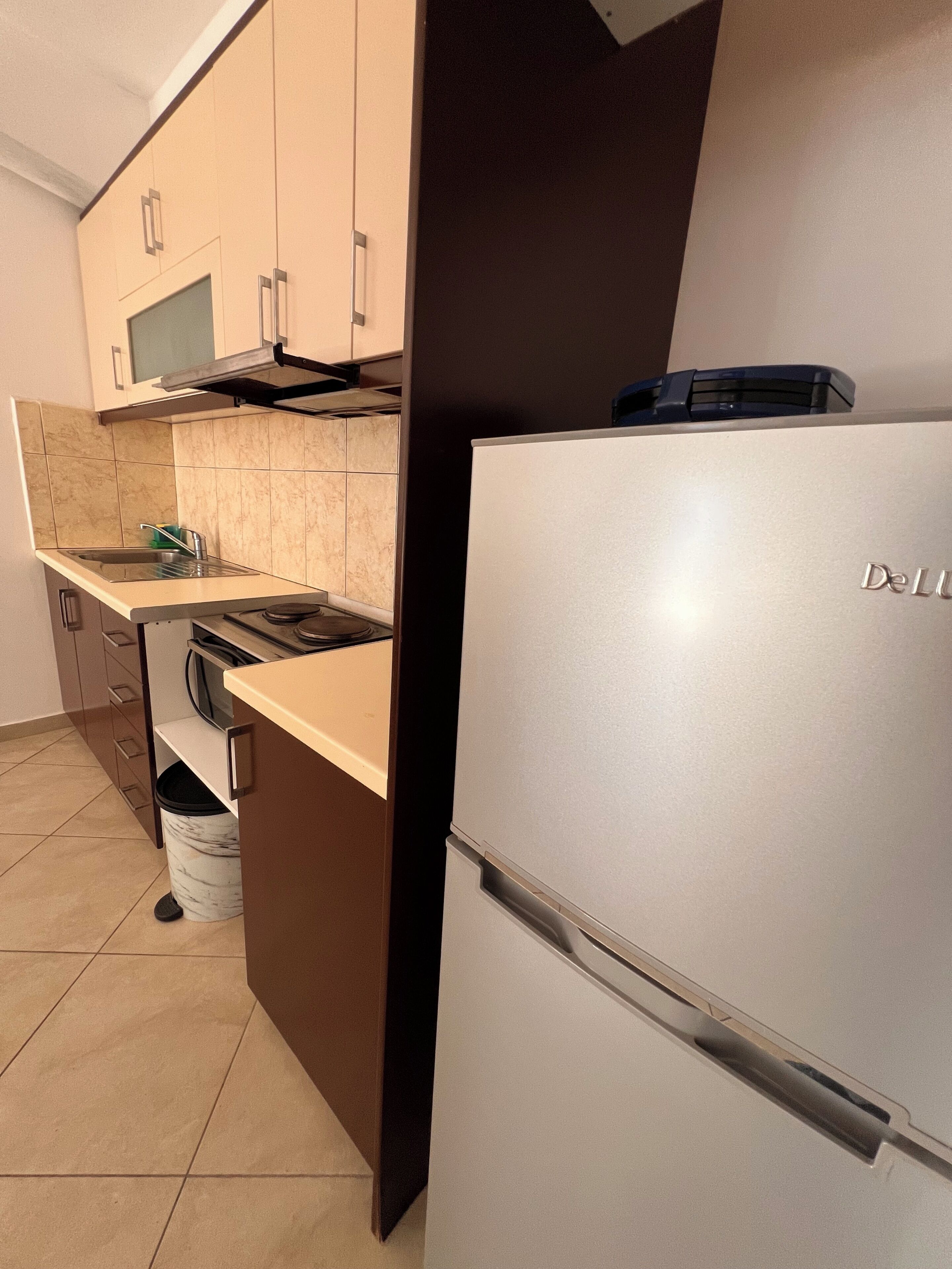 A kitchen with a DeLuxe refrigerator, a microwave, and a sink.