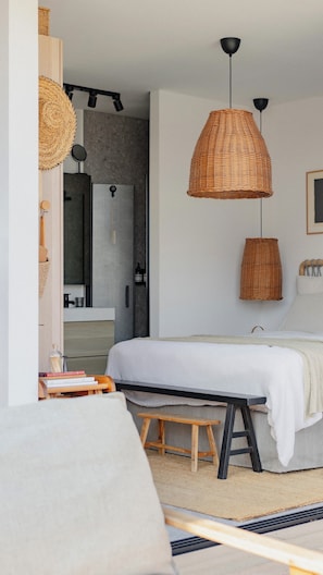 Une chambre à coucher avec un lit, un banc en bois, une suspension en osier et un miroir.