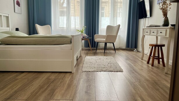 Un dormitorio moderno con una cama, una silla, un escritorio y un televisor.