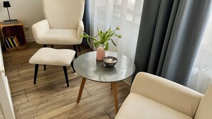 Una sala moderna con sofá, sillón y una mesita con una planta.
