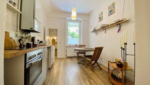 Una cocina compacta con electrodomésticos modernos, una zona de comedor con mesa y sillas de madera, y vistas a través de un ventanal.