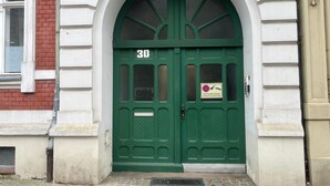 Una puerta doble verde con el número 30, un letrero que prohíbe estacionar y una rejilla metálica en el suelo.