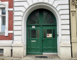 A green double door with the number 30, a sign prohibiting parking, and a metal vent on the ground. - Cozy vacation apartment in a good location (Görlitz)