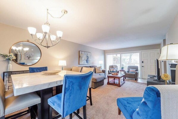 A dining area with a chandelier, a round mirror, and a dining table with chairs.