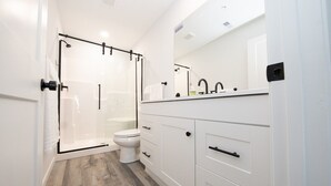 Ein modernes Badezimmer mit Duschkabine aus Glas, Toilette und weißen Schränken.