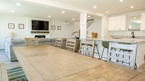 Eine moderne Küche mit weißen Schränken, einem eingebauten Herd und einem Essbereich mit Holztisch und Stühlen.