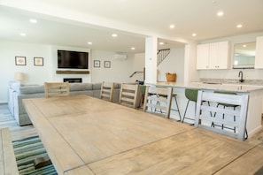 A modern kitchen with white cabinets, a built-in stove, and a dining area with a wooden table and chairs.
