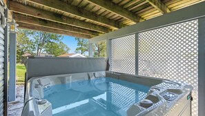 A covered outdoor hot tub with a wooden ceiling and a lattice screen.
