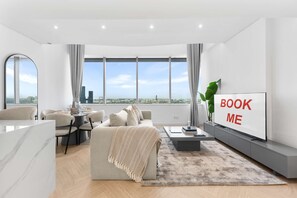 En moderne stue med sofa, sofabord og et tv, der viser 'BOOK ME'.