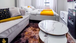 Een moderne hotelkamer met een bank, een bed, een televisie en een marmeren salontafel.
