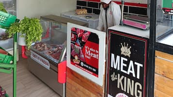 A butcher shop interior with a meat display, a weighing scale, and a sign advertising fresh meat delivery.