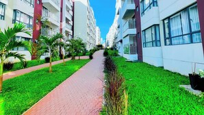 Een pad tussen moderne appartementen met balkons, omringd door verzorgde groenvoorziening.