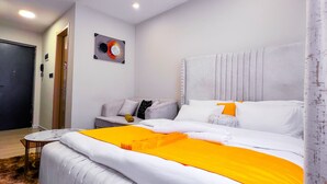 Een moderne hotelkamer met een groot bed, een klein tafeltje en een hoofdbord met ingebouwde verlichting.