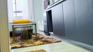 Een moderne keuken met een koelkast, een eethoek met een tafel en stoelen, en uitzicht buiten door een raam.