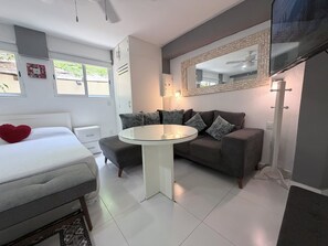 Ein modernes Schlafzimmer mit einem Bett, einem runden Tisch, einer Couch und einem großen Spiegel.
