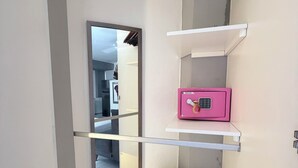 Une armoire blanche avec deux tiroirs et un coffre-fort rose placé sur une étagère.