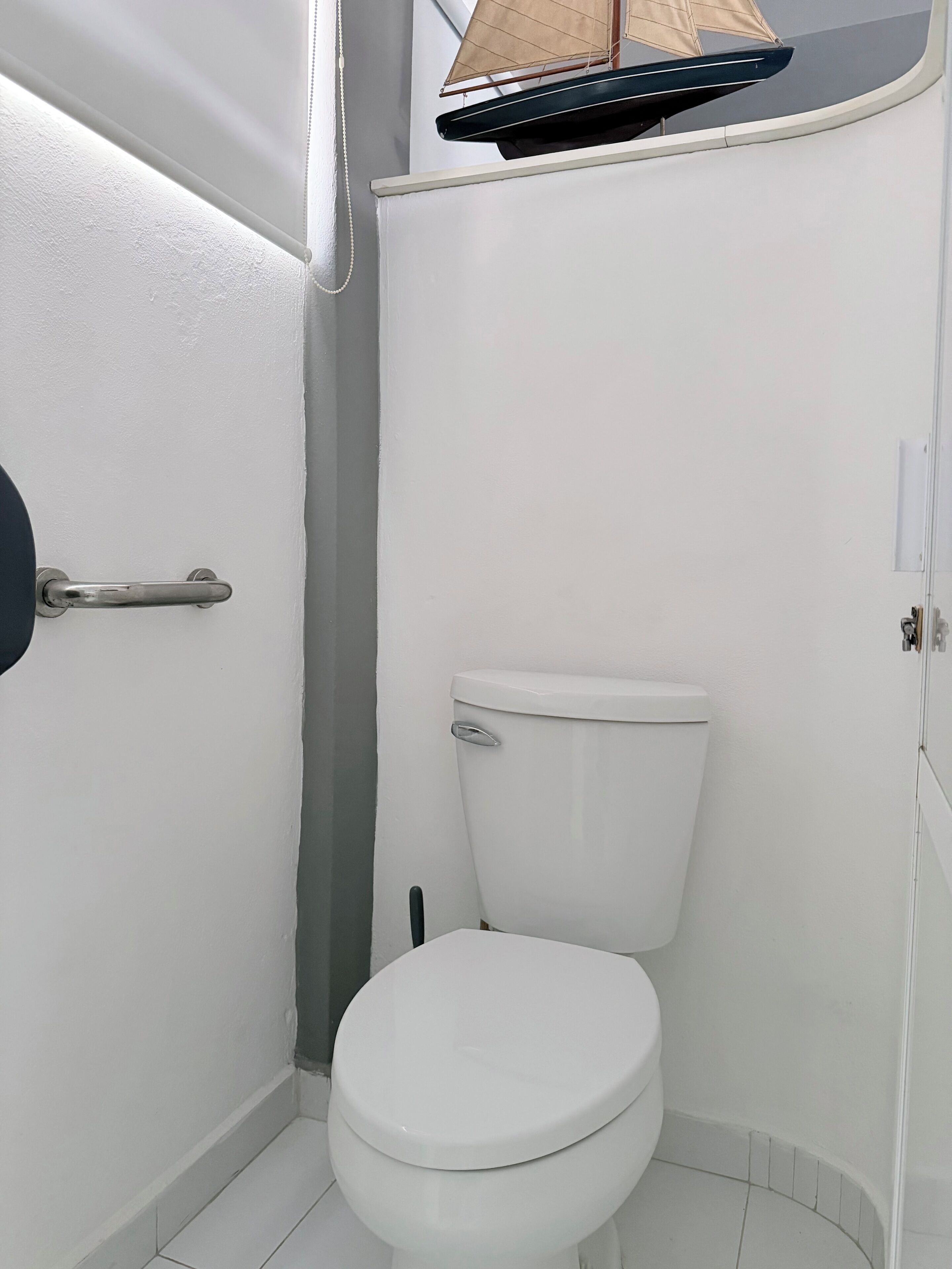 Eine weiße Toilette in einem kleinen Badezimmer mit Türgriff und Handtuchhalter.
