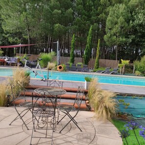 Zona de piscina con sillas de descanso, una mesa y una pérgola.