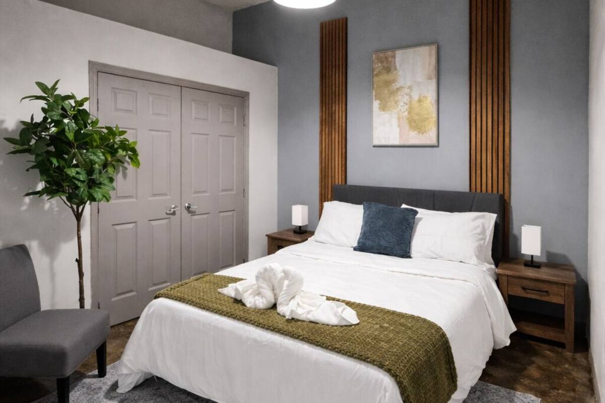 A modern bedroom with a bed, bedside tables, a plant, and a door.