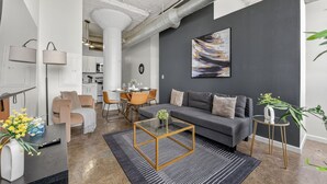 A modern living room with a sofa, coffee table, and dining area. - Cold Storage by Stylish Stays (Kansas City)