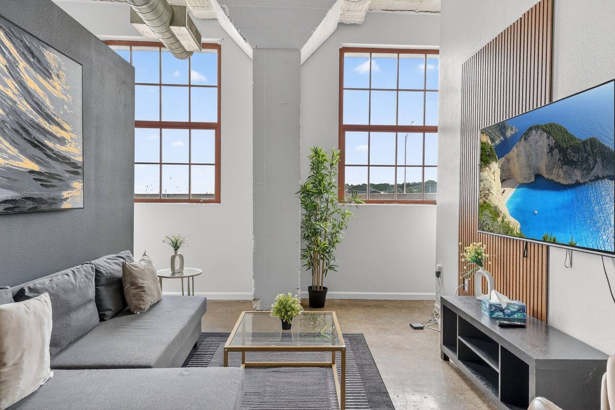 A modern living room with a sofa, coffee table, and a TV mounted on the wall.