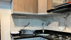 A modern kitchen with wooden cabinets, a black countertop, a stove, and a microwave. - Oceana Suites Cartagena de Indias (Cartagena)