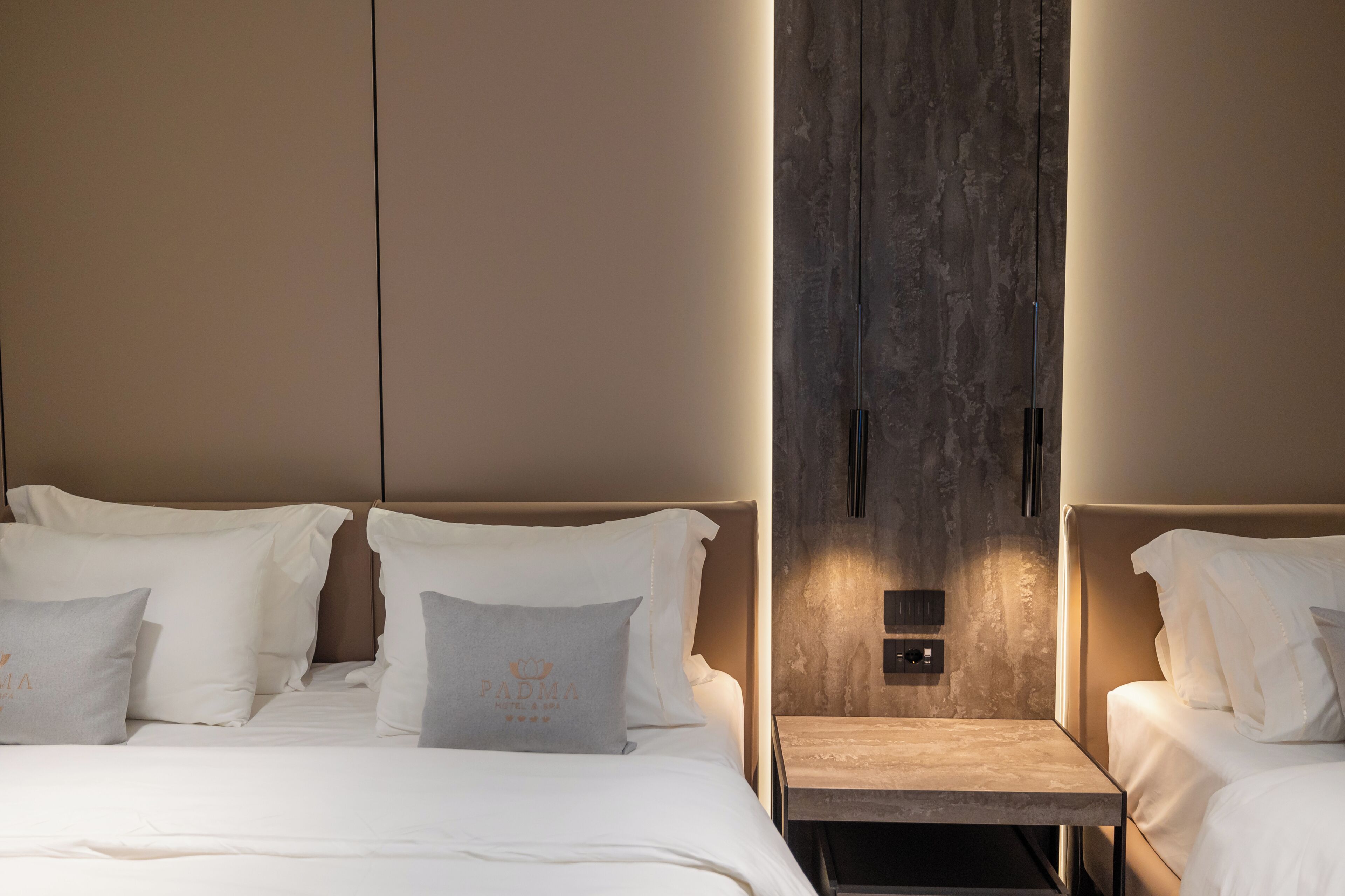 A hotel room with a bed, two bedside tables, and a wall-mounted light fixture.