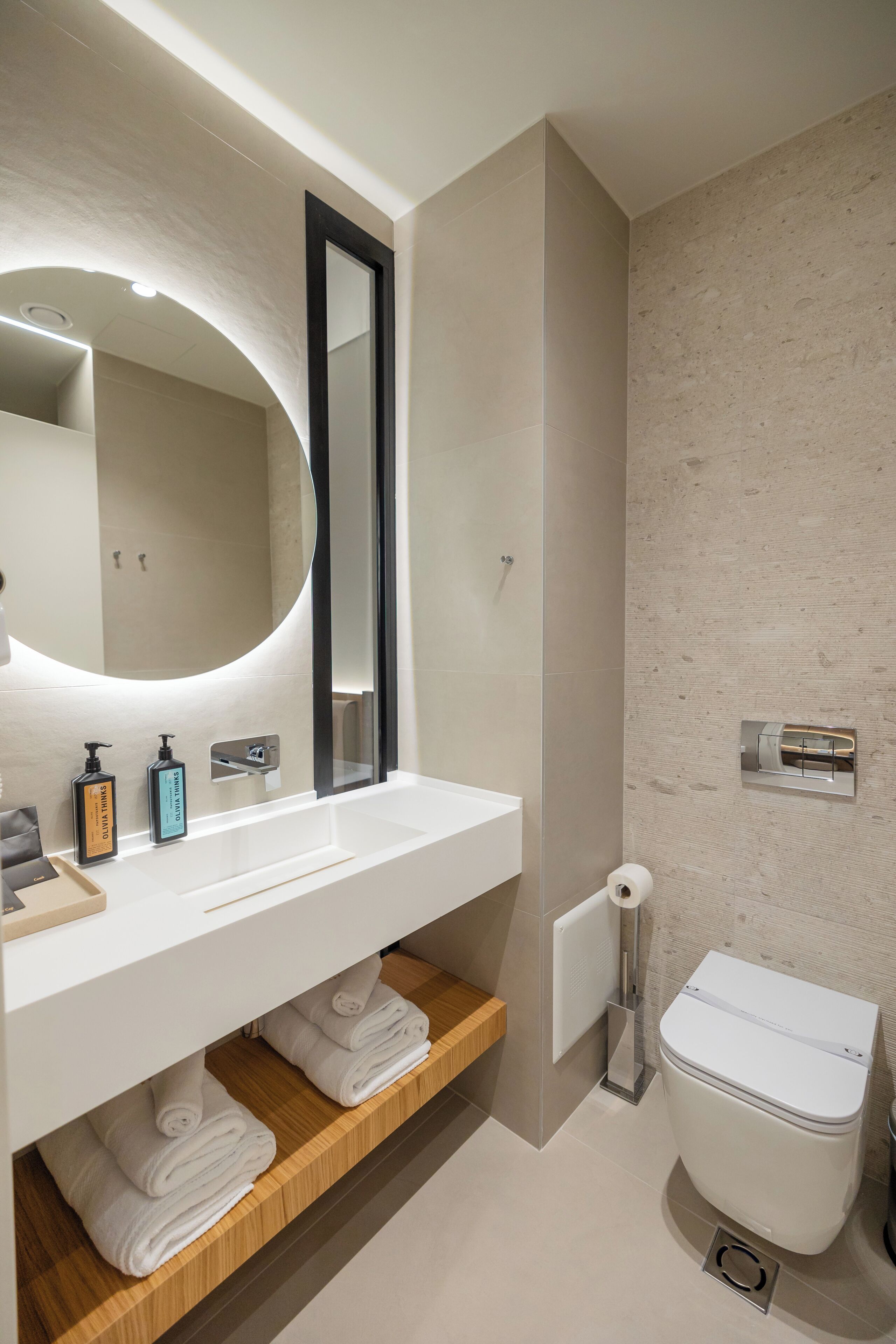 Een moderne badkamer met een witte wastafel, spiegel en toilet.