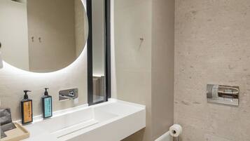 Een moderne badkamer met een witte wastafel, spiegel en toilet.