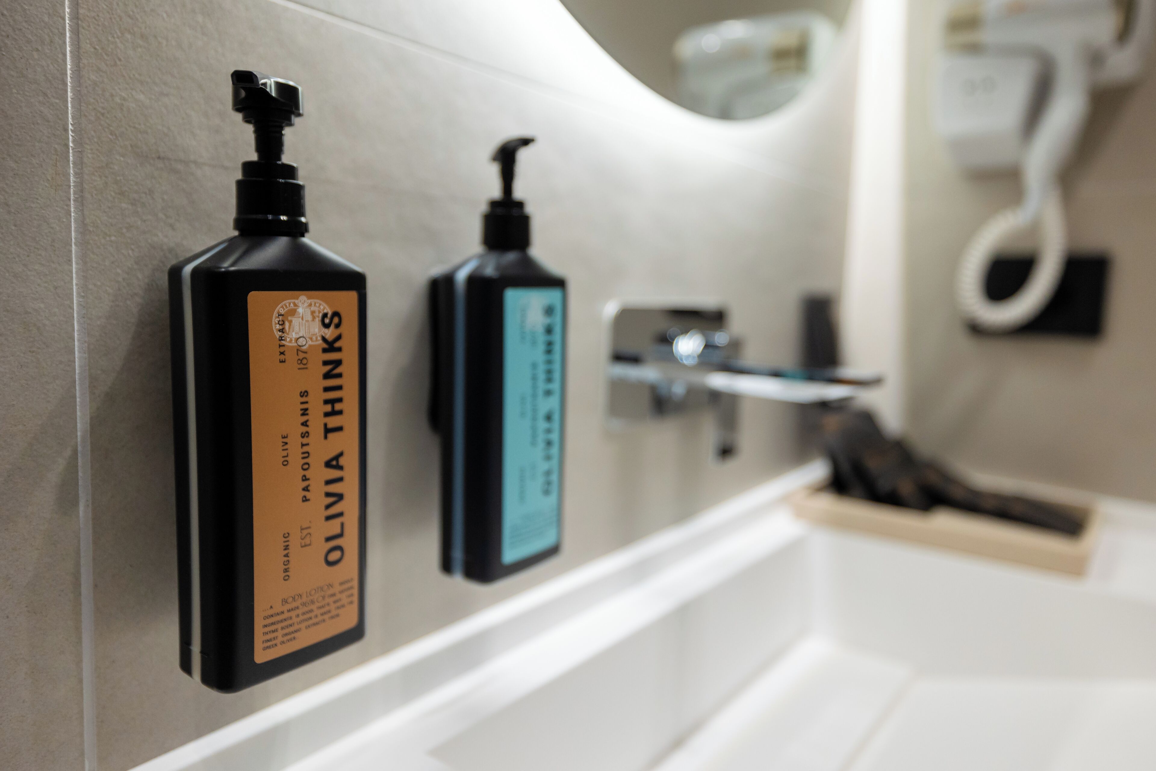 A bathroom with a white bathtub, a towel rack, and two bottles of olive oil on the wall.