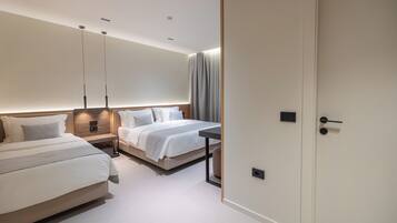 Ein modernes Hotelzimmer mit zwei Betten, einem Nachttisch, einem Schreibtisch und einer Tür.