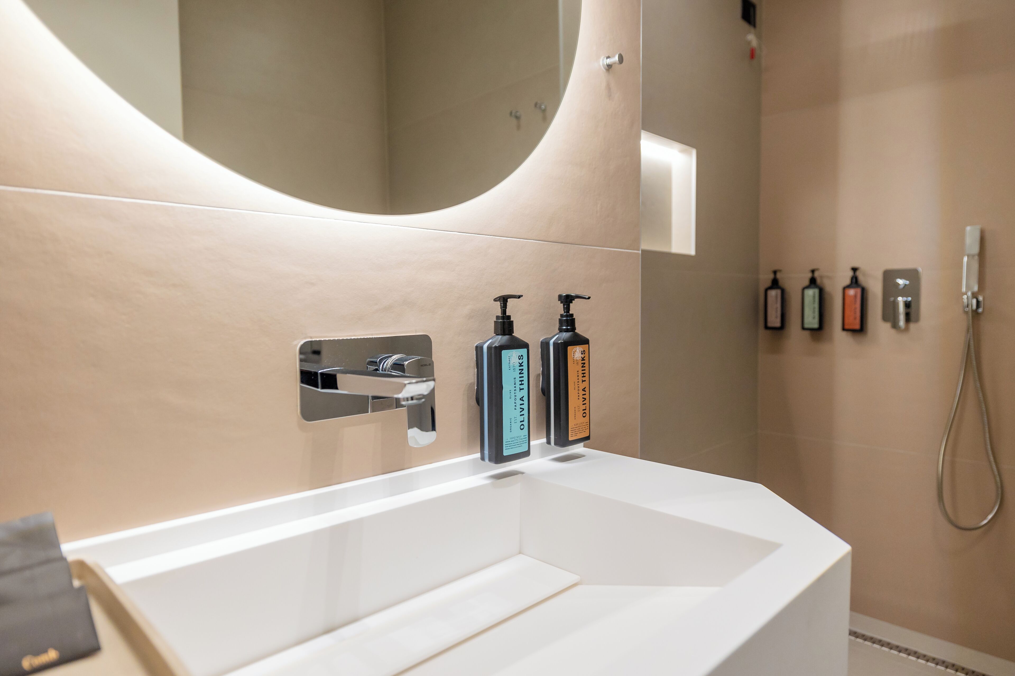 A modern bathroom with a large mirror, a white sink, and two soap dispensers.