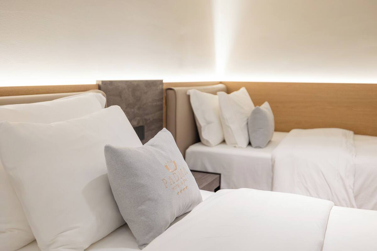 A hotel room with a bed, pillows, and a headboard.