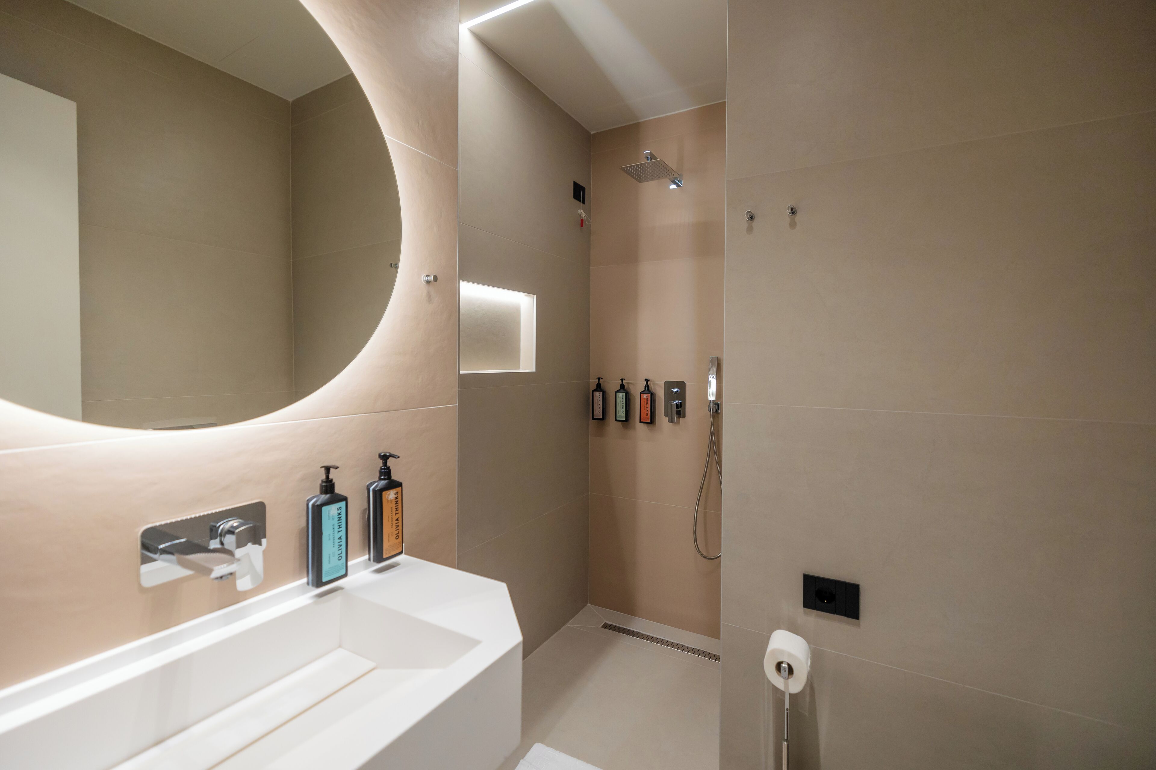 Un bagno moderno con un ampio specchio, due lavandini, una doccia e un water.