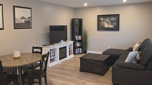 Ein Wohnzimmer mit Esstisch, Sofa, Bücherregal und Fernseher.