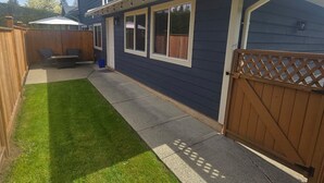 Ein Wohnhaus mit überdachter Terrasse, umzäunter Garten und Holztor.