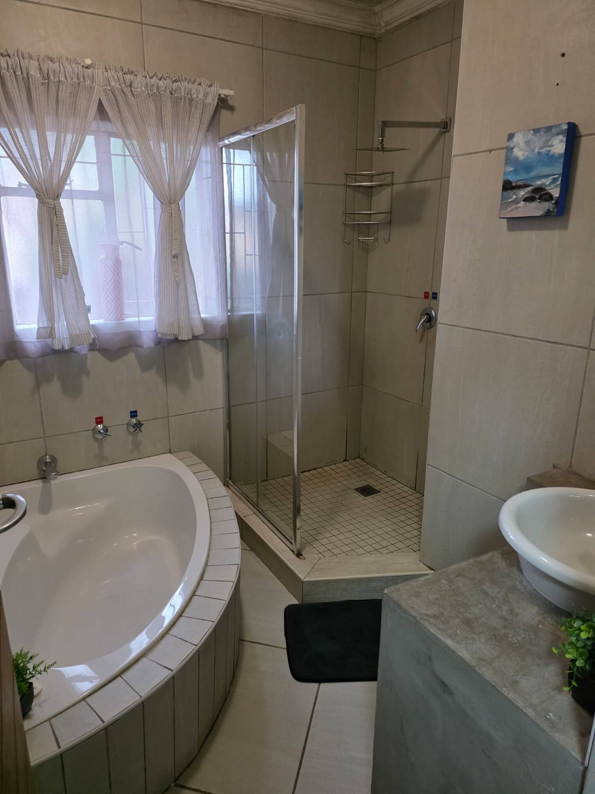 A bathroom with a bathtub, shower, sink, and a glass door shower stall.