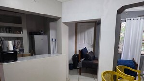 A compact living space with a kitchenette, a bed, and a small seating area with yellow chairs. - The Pot Faerie Glen in Pretoria (Pretoria)