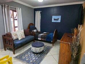 Une pièce comprenant un canapé, un lit, une petite table, une chaise et un téléviseur fixé au mur.