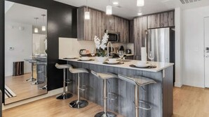 A modern kitchen with a central island, bar stools, and pendant lighting.